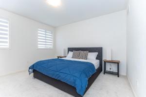 a white bedroom with a bed with a blue blanket at Home in Waterdown in Hamilton