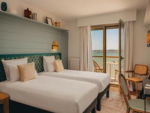 a hotel room with two beds and a balcony at Hôtel Les Brises in La Rochelle