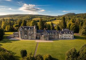 an aerial view of a large house on a green field at Lomond Castle Penthouse in Luss