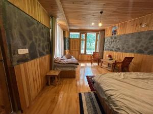 a bedroom with two beds and a table and chairs at Trio Nest in Jibhi
