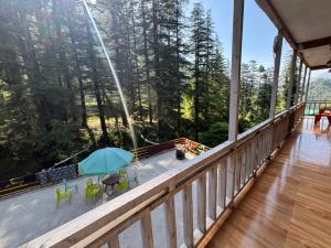 a balcony of a house with a view of the forest at Trio Nest in Jibhi