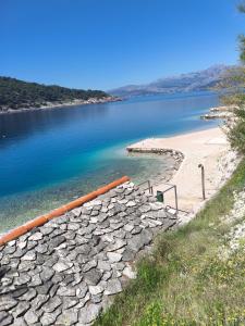 a beach with a rock wall next to a body of water at Nice postion, belle vue in Pučišća