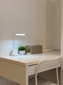 a white desk with a lamp and a chair at Calm & Comfy at Sky House BSD in Cilenggang