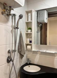 a bathroom with a shower and a sink and a mirror at Calm & Comfy at Sky House BSD in Cilenggang