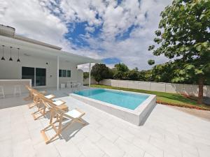 a swimming pool with chairs and a table and a house at The paperwhite poolvilla khaoyai in Ban Tha Chang