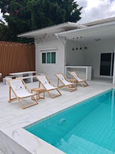 a group of lounge chairs next to a swimming pool at The paperwhite poolvilla khaoyai in Ban Tha Chang