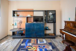 a living room with a blue entertainment center and a piano at Tiz Home il Tuo Rifugio di Charme nel Cuore della Sicilia autentica in Canicattì