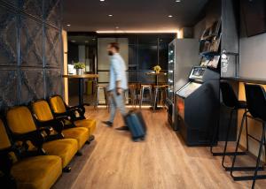 a man walking with a suitcase in a living room at Airhostel Barcelona Airport 24h in El Prat de Llobregat