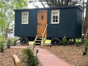 a tiny house on wheels parked in a yard at Half Moon Shepherds Huts in Plumpton