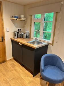a kitchen with a sink and a blue chair at Half Moon Shepherds Huts in Plumpton