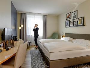 a woman talking on a phone in a hotel room at Mercure Hotel Bochum City in Bochum