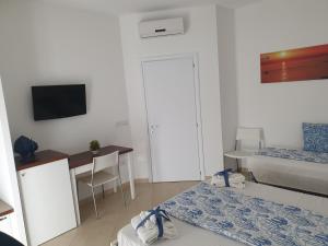 a small room with a bed and a desk and a television at B&B Colori del Salento in Presicce