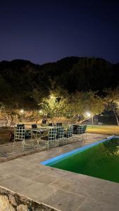 a table and chairs next to a swimming pool at night at The chocolate frog in Udaipur