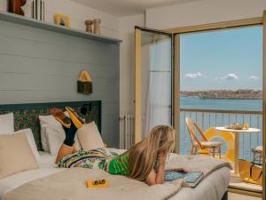a woman laying on a bed with a book at Hôtel Les Brises in La Rochelle +64 photos