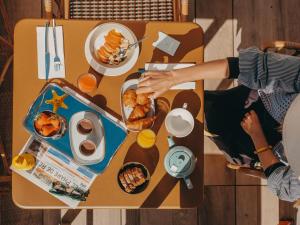 a woman eating food on a table with plates of food at Hôtel Les Brises in La Rochelle
