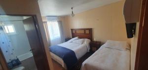 a hotel room with two beds and a mirror at Hostal Internacional Valdivia in Valdivia