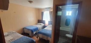 a small room with three beds and a toilet at Hostal Internacional Valdivia in Valdivia