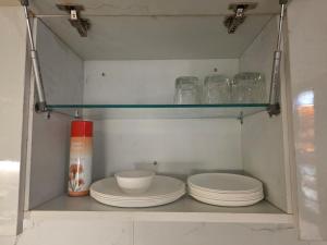 a shelf with plates and bowls in a cabinet at The Cozy Theory in Kharar