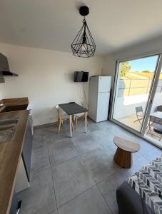 a kitchen with a refrigerator and a table in a room at Entre Terre et Mer, logement cosy in Poussan +10 photos