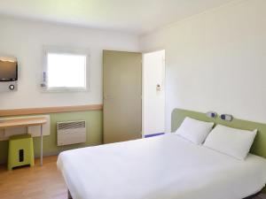 a bedroom with a large white bed and a window at Ibis budget Saint-Étienne stade in Saint-Étienne