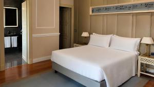 a bedroom with a large white bed and a bathroom at Radisson Blu GHR Rome in Rome +187 photos