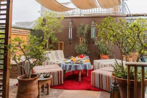 a patio with tables and chairs and potted trees at Riad Al Ibtikar in Marrakesh