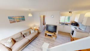 a living room with a couch and a kitchen at 39 Strawberry Hill, Tolroy Manor in Hayle