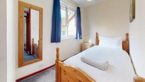 a bedroom with a wooden bed and a mirror at 39 Strawberry Hill, Tolroy Manor in Hayle +16 photos