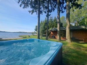 a hot tub with a view of the water at Mazurska Ostoja na Półwyspie - domki przy samym jeziorze in Mrągowo