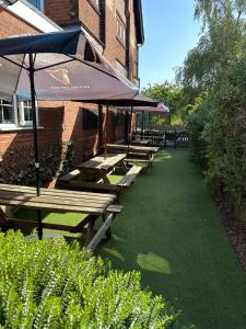 a row of picnic tables with umbrellas in front of a building at The Cross Keys in Worthington