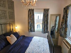 a bedroom with a bed and a chandelier and a window at Quirky hideout in town centre in Wimborne Minster