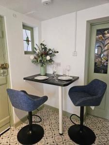 a table with two chairs and a table with wine glasses at Quirky hideout in town centre in Wimborne Minster