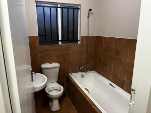 a bathroom with a toilet and a tub and a window at Namahadi Stay in Vereeniging