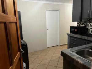 a kitchen with a door and a sink and a refrigerator at Namahadi Stay in Vereeniging