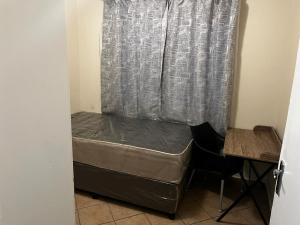 a bed in a room with a curtain and a desk at Namahadi Stay in Vereeniging