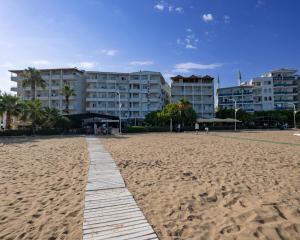 a boardwalk on a beach with buildings in the background at Seymen Otel in Kizkalesi