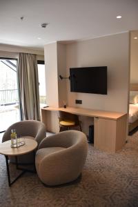 a hotel room with a desk with chairs and a television at Hotel Dom in Studenci