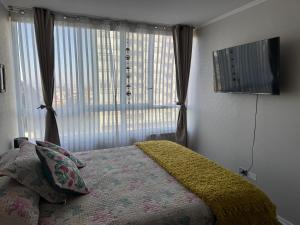 a bedroom with a bed and a large window at Acogedor apartamento in Quilpué