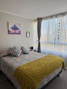 a bedroom with a bed with a yellow blanket and a window at Acogedor apartamento in Quilpué +18 photos