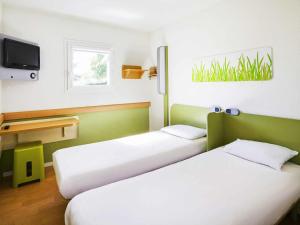 a room with two beds and a tv at ibis budget Chartres in Chartres