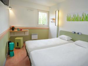 a hotel room with two beds and a window at ibis budget Toulouse Centre Gare in Toulouse +55 photos