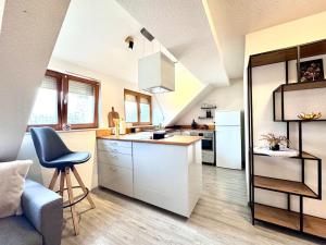 a kitchen with white cabinets and a blue chair at Ferienwohnung Artemis in Eggingen