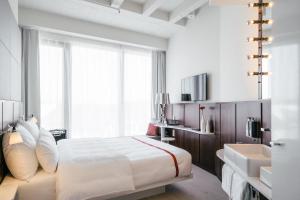 una camera da letto con un grande letto bianco e un lavandino di Ruby Lilly Hotel Munich by IHG a Monaco