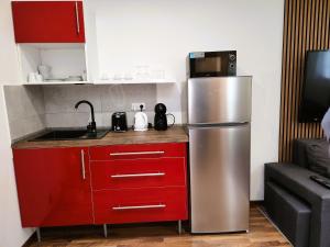 a kitchen with a stainless steel refrigerator and red cabinets at Apartment v podzámčí in Františkovy Lázně
