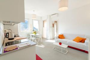 a white living room with a couch and a kitchen at Appartamento x 4 con wi-fi, park free, a 10 minuti dal centro di Garda in Garda