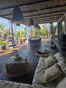 a deck with a couch and a table and chairs at chambres d hôtes villa del sole in Puget-sur-Argens