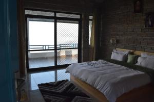 a bedroom with a bed and a large window at Rudraa Himalayan Retreat in Hawālbāgh +5 photos