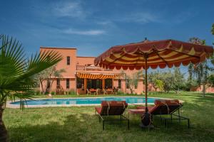 a pool with chairs and an umbrella next to a house at Villa Samadhi - Luxury & Serenity in Marrakesh