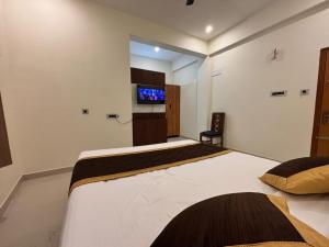 a bedroom with two beds and a flat screen tv at Thamira Grand palace in Agastīswaram