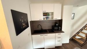 a kitchen with white cabinets and a sink at Amara in Siegburg +5 photos